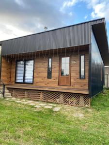 a house with a black roof and wooden facade at Los Ciruelos Cabin in Calbuco