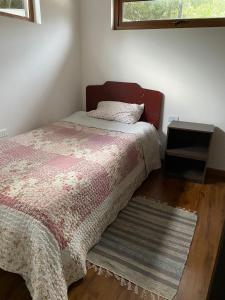 a bedroom with a bed and a rug and a window at Los Ciruelos Cabin in Calbuco
