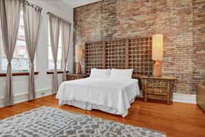 a bedroom with a white bed and a brick wall at Luxe 220 Suite 4 in Wilmington