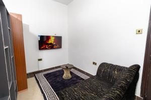 a living room with a couch and a tv on a wall at MIG Studios in Nakuru