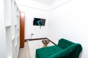 a living room with a green couch and a tv at MIG Studios in Nakuru