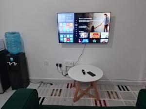 a room with a white table and a tv on the wall at Magenche in Ongata Rongai 