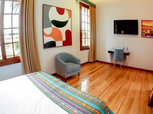 a bedroom with a bed and a chair and a television at Hotel Boutique Circasiana Palace in Quito
