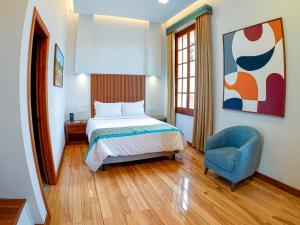 a bedroom with a bed and a blue chair at Hotel Boutique Circasiana Palace in Quito