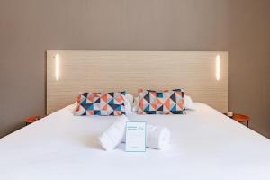 a white bed with towels and a sign on it at Appart'City Classic Lyon Part Dieu Garibaldi in Lyon +12 photos