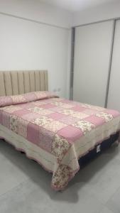 a bed with a pink and white quilt on it at Brickell 3A in Tigre +18 photos