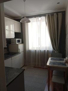 a kitchen with a table and a window with curtains at Gray in Ternopil