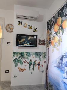 a wall with a tv on a wall with birds and butterflies at House Le Antiche Mura in Castel Volturno