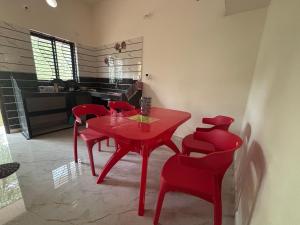 a red dining room table and red chairs in a kitchen at Athityam Home Stay in Honāvar