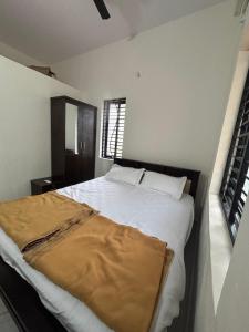 a bedroom with a large white bed with a window at Athityam Home Stay in Honāvar +2 photos