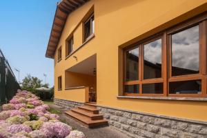 a yellow house with large windows and pink flowers at Casa Maldivas - Cerca playa de Barro/ Niembro in Posada de Llanes
