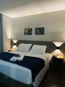 a large bed in a hotel room with two lamps at Gaivotas Praia Hotel in Florianópolis