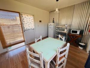 a kitchen with a table and chairs and a refrigerator at El Atardecer Monoambiente in Puerto Pirámides