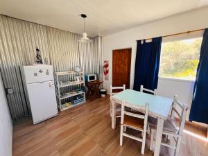 a kitchen with a table and a white refrigerator at El Atardecer Monoambiente in Puerto Pirámides