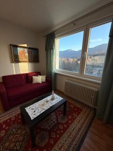 a living room with a red couch and large windows at Útulný apartmán v Jizerkách in Hejnice +21 photos