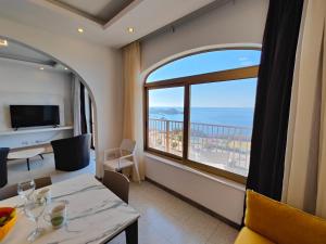 a living room with a table and a large window at Seafront 3 bed Panoramic SeaViews Apt B7- in Qbajjar