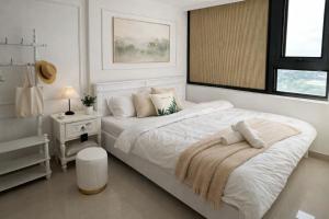 a white bedroom with a large bed and a window at Hue Oi Homestay - Spacious 3-Bedroom Apartment with Balcony & Pool in Hue