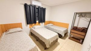 a room with two beds and a mirror at Sobrado de luxo em condomínio in Araçatuba
