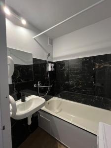 a black tiled bathroom with a sink and a bath tub at Kerulis Apartments in Vilnius +4 photos