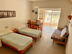 a room with three beds and a table and chairs at Apartamentos, Edificio Pujolets Es Pujols-Playa in Es Pujols
