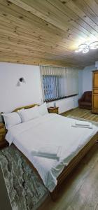 a large bed in a room with a wooden ceiling at Casa LUMINITA in Cîrlibaba