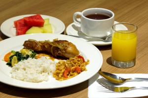 a plate of food with rice and a cup of orange juice at Vinotel Cirebon in Cirebon