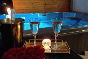 two glasses of water on a tray next to a tub at Apartament Heaven SPA z prywatnym jacuzzi i sauną in Zdów