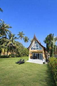 a house with two chairs in a yard with palm trees at Rosdao Beachfront Villa in Ban Khlong Son