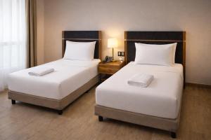 Zwei Einzelbetten in einem Hotelzimmer mit einer Lampe in der Unterkunft Hotel Vía Norte Inn - Nuevo - Estacionamiento gratis - Ubicación estratégica in Tuxtla Gutiérrez