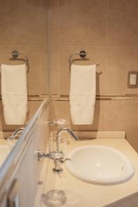 a bathroom with a sink and two towels on a wall at Patagonia Hotel in Caleta Olivia