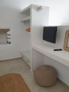 a white living room with a tv and a stool at Kalypso Tholos in Astypalaia