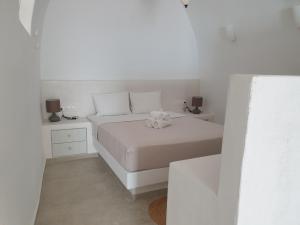 a white bedroom with a bed and two night stands at Kalypso Tholos in Astypalaia