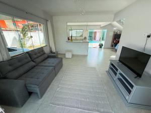 a living room with a couch and a flat screen tv at House in Jaconé in Maricá