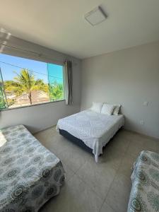 a bedroom with two beds and a large window at House in Jaconé in Maricá +16 photos