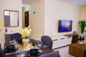 a dining room with a table with chairs and a tv at K&K Stays in Nakuru