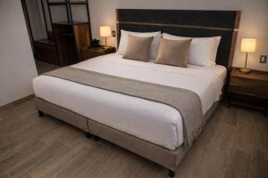 ein großes Bett in einem Hotelzimmer mit zwei Lampen in der Unterkunft Hotel Vía Norte Inn - Nuevo - Estacionamiento gratis - Ubicación estratégica in Tuxtla Gutiérrez