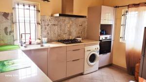 a kitchen with a sink and a washing machine at Jugroop Beach House in Baie du Tombeau