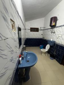 a bathroom with a blue sink and a toilet at Peaceful Mountain Cottage in Bhīm Tāl