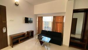 a living room with a black couch and a window at Sylhet La Vista in Sylhet