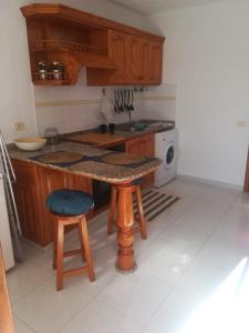 a kitchen with wooden cabinets and a table and stool at Apartamentos Punta Mujeres alto derecha in Punta Mujeres