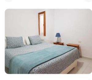 a bedroom with a bed with a blue blanket at Apartamentos Punta Mujeres alto derecha in Punta Mujeres