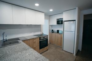 a kitchen with white cabinets and a sink and a refrigerator at Apartamento Floral al centro de Palamós con Wi-Fi in Palamós
