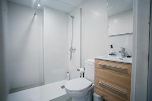 a white bathroom with a shower and a toilet at Apartamento Floral al centro de Palamós con Wi-Fi in Palamós +13 photos