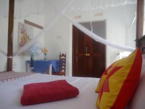 a bedroom with a bed with a red and yellow pillow at Sanaya Homestay in Tangalle