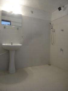 Un baño blanco con lavabo y ducha. en Sanaya Homestay, en Tangalle