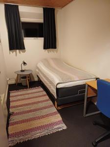 a small bedroom with a bed and a desk and a rug at KLAUSIEVEJ B&B in Ulfborg