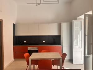 a kitchen with a table and some orange chairs at Vico Rosso - Milù Holidays La Maddalena in La Maddalena +18 photos