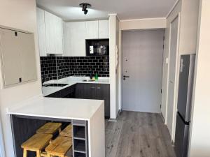 a kitchen with a white counter and wooden stools at Muelle Barón - Terminal de Buses in Valparaíso +13 photos
