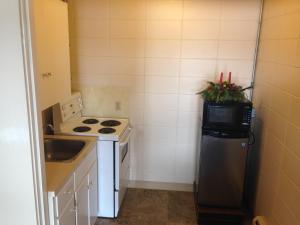 a small kitchen with a stove and a refrigerator at Siesta Motel in Olds