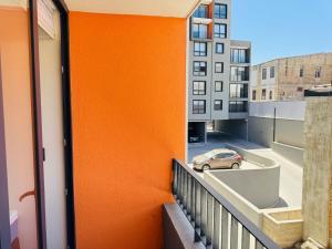a balcony with an orange wall and a car on a street at Muelle Barón - Terminal de Buses in Valparaíso